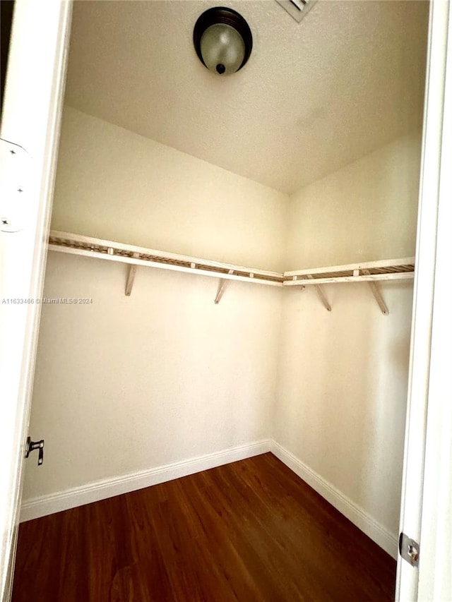 walk in closet with dark wood-type flooring