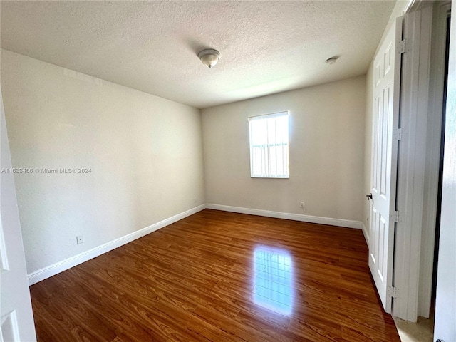 empty room featuring a textured ceiling and dark hardwood / wood-style floors