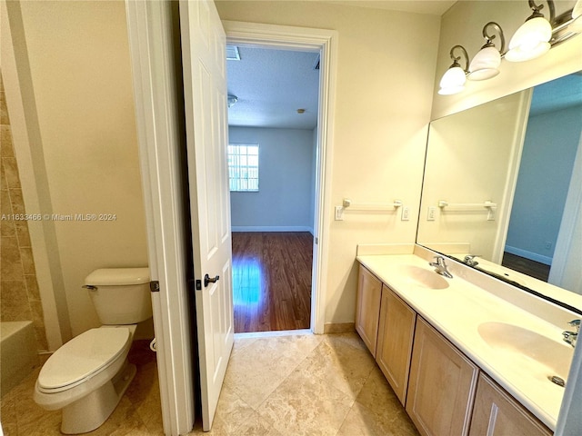 bathroom with vanity, a bathtub, wood-type flooring, a textured ceiling, and toilet