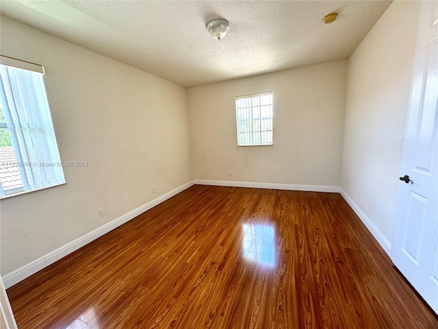 spare room featuring a textured ceiling and dark hardwood / wood-style floors