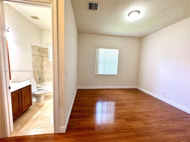 unfurnished bedroom featuring a textured ceiling and light hardwood / wood-style flooring