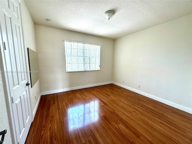 spare room featuring a textured ceiling and hardwood / wood-style flooring