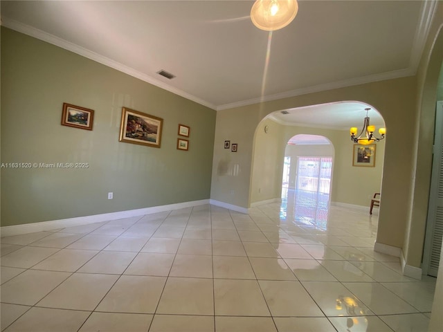 empty room with light tile patterned floors, crown molding, and a chandelier