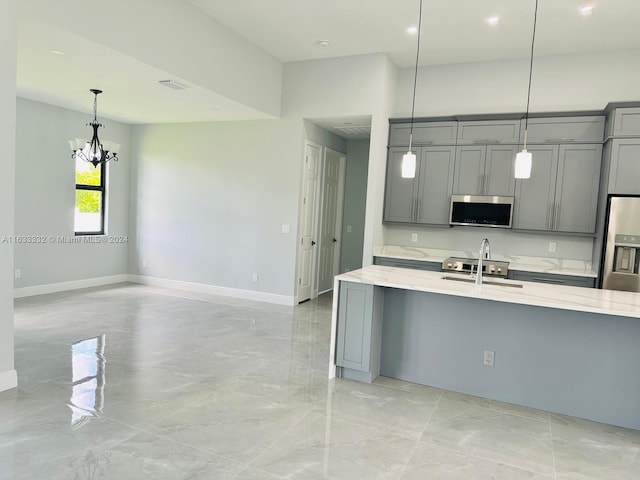 kitchen featuring gray cabinetry, stainless steel appliances, light stone countertops, and pendant lighting