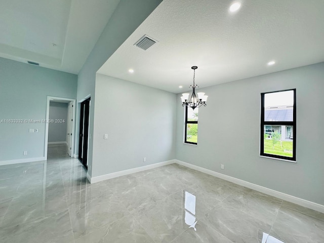 empty room featuring a textured ceiling and a notable chandelier