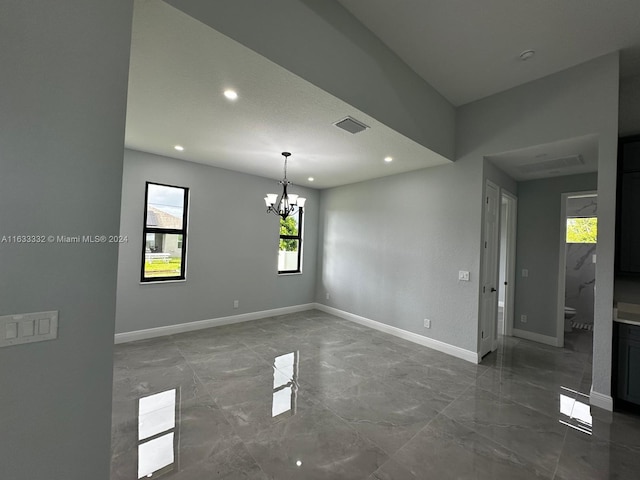 unfurnished room with a notable chandelier and a textured ceiling