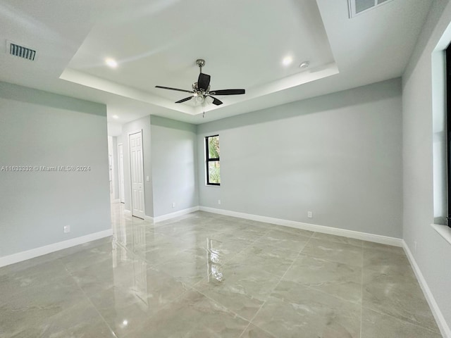 unfurnished room with a raised ceiling and ceiling fan