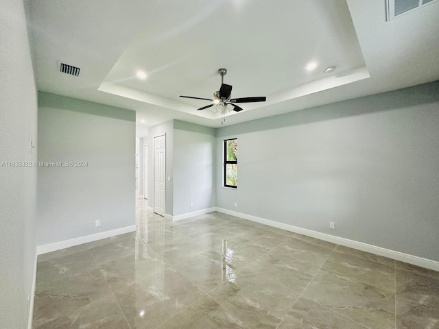 spare room with ceiling fan and a raised ceiling