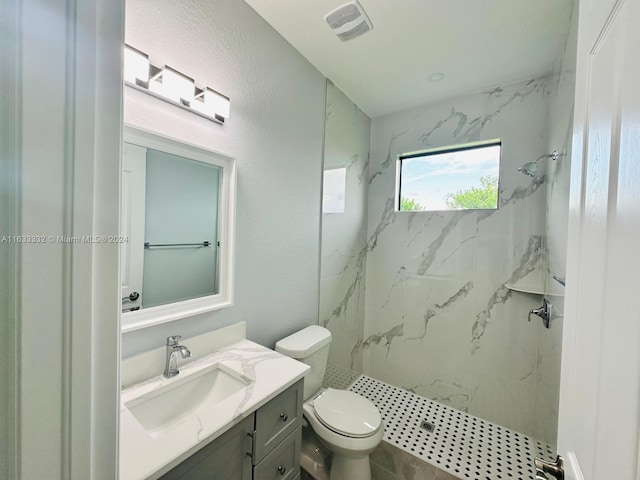 bathroom with vanity, toilet, and tiled shower