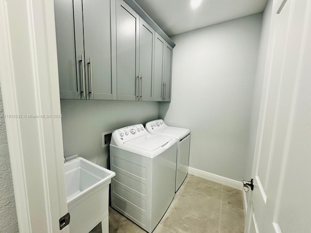 washroom featuring washing machine and clothes dryer, cabinets, and sink