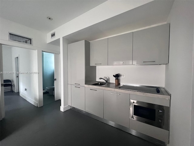 kitchen with gray cabinetry, visible vents, a sink, and black electric stovetop