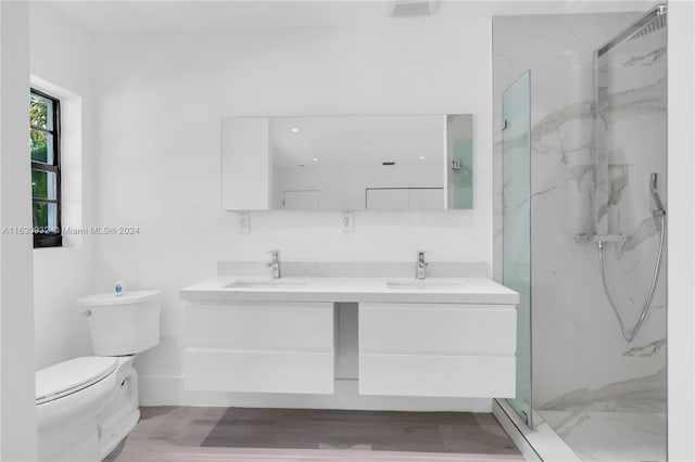 bathroom featuring wood-type flooring, double sink vanity, toilet, and an enclosed shower