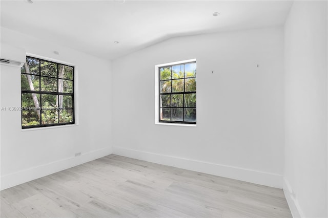 unfurnished room featuring a wall mounted air conditioner, light hardwood / wood-style flooring, and lofted ceiling