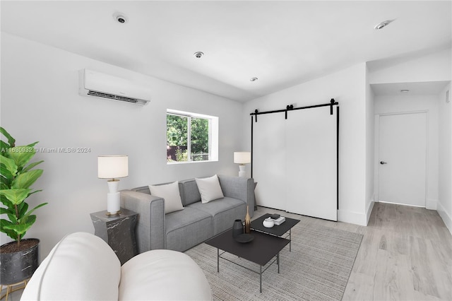 living room featuring a wall mounted air conditioner, a barn door, lofted ceiling, and light hardwood / wood-style floors