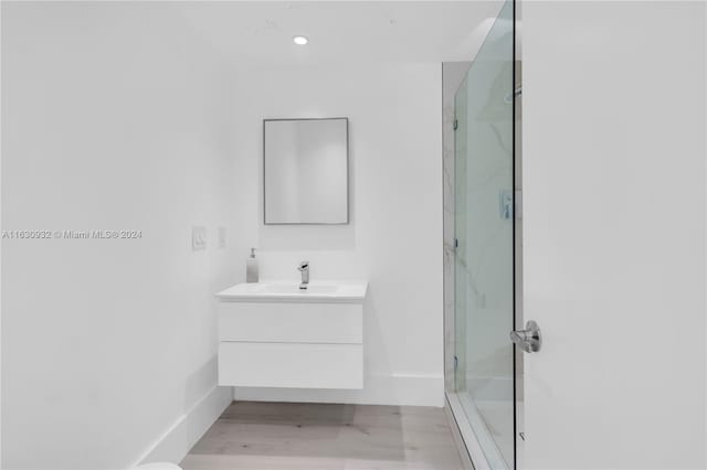 bathroom with wood-type flooring, vanity, and an enclosed shower