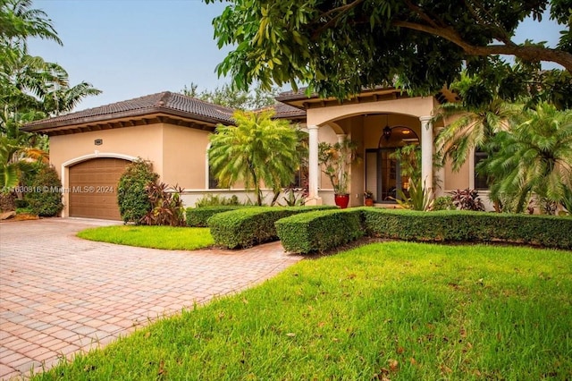 mediterranean / spanish-style house featuring a garage, ceiling fan, and a front yard