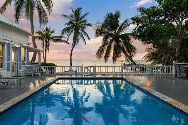 pool at dusk featuring a water view