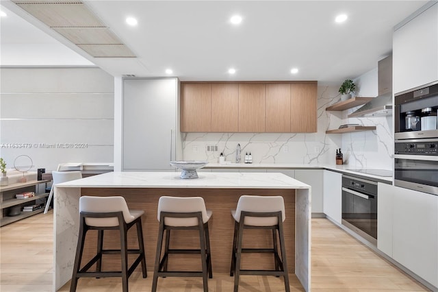 kitchen featuring white cabinets, backsplash, light hardwood / wood-style floors, and a kitchen island