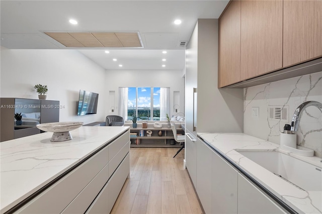 kitchen featuring light wood-type flooring, light stone counters, sink, and light brown cabinetry