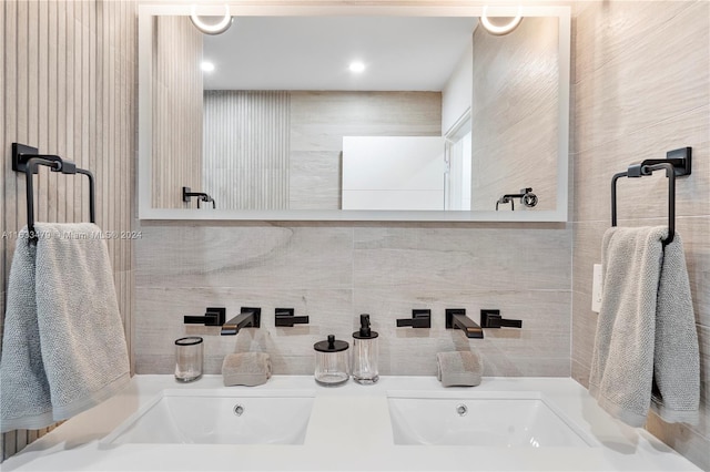 bathroom with double sink and tile walls