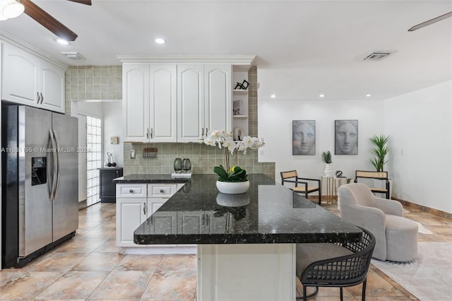 kitchen with stainless steel refrigerator with ice dispenser, white cabinets, dark stone countertops, and ceiling fan