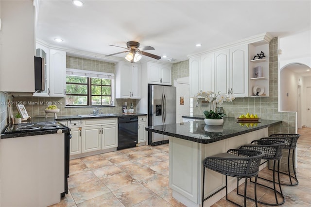 kitchen with appliances with stainless steel finishes, a breakfast bar area, backsplash, and ceiling fan