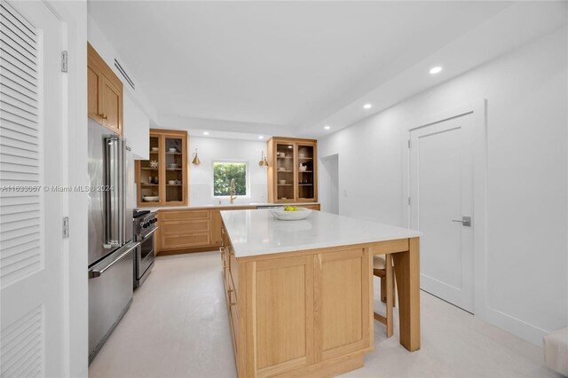 kitchen with light brown cabinetry, a center island, stainless steel appliances, a breakfast bar, and sink