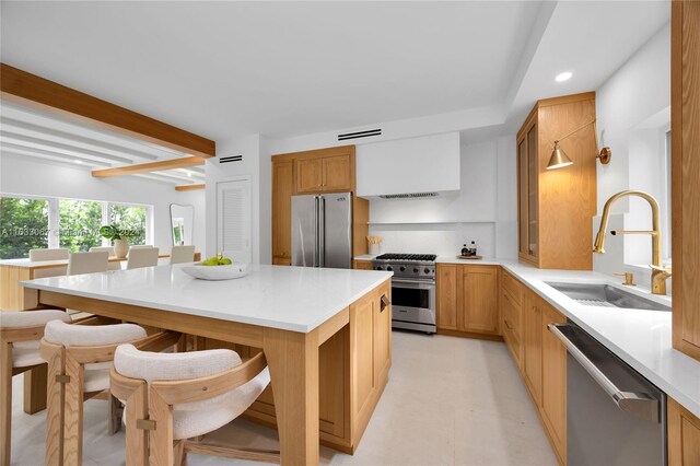 kitchen featuring a kitchen island, sink, beamed ceiling, and premium appliances