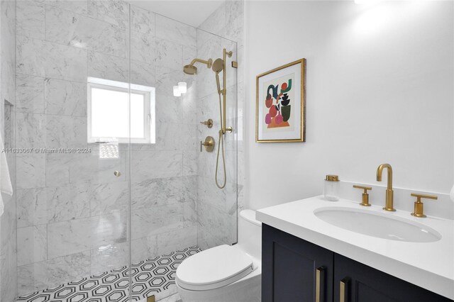 bathroom featuring toilet, a tile shower, and vanity