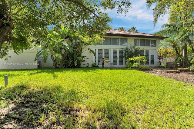 back of property featuring a lawn and french doors