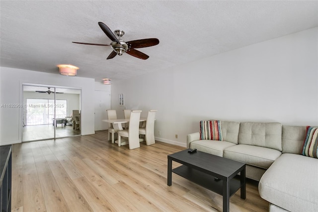 living room featuring a textured ceiling, light hardwood / wood-style flooring, and ceiling fan