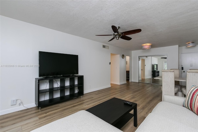 living room featuring hardwood / wood-style floors, ceiling fan, and a textured ceiling