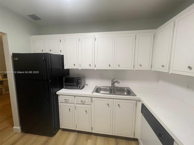 kitchen with black fridge, stainless steel dishwasher, sink, light hardwood / wood-style flooring, and white cabinetry