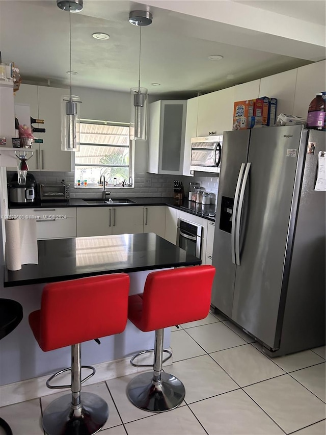 kitchen featuring a breakfast bar area, tasteful backsplash, stainless steel appliances, sink, and white cabinetry