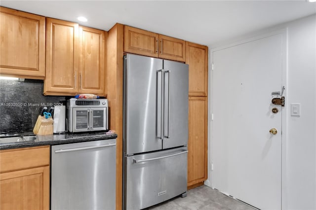 kitchen with appliances with stainless steel finishes, sink, decorative backsplash, and dark stone counters