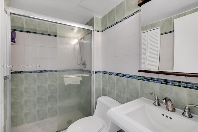 bathroom with sink, a shower with door, tile walls, backsplash, and toilet