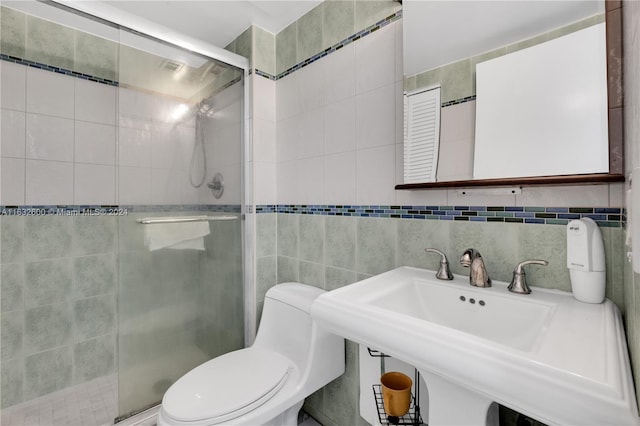 bathroom with sink, tile walls, backsplash, toilet, and a shower with door