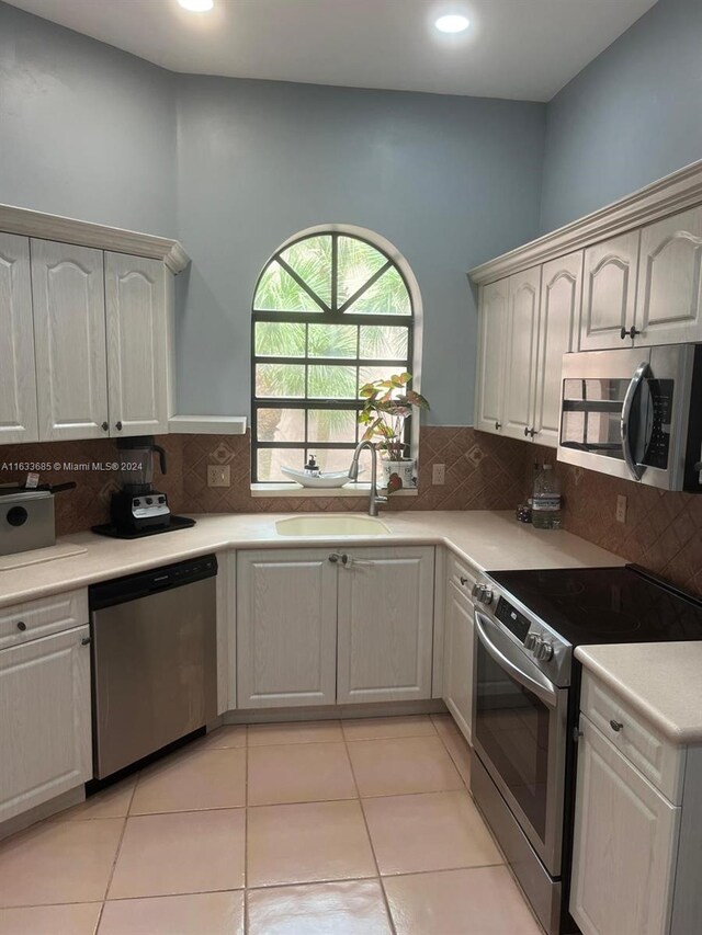 kitchen featuring tasteful backsplash, sink, light tile patterned floors, and stainless steel appliances