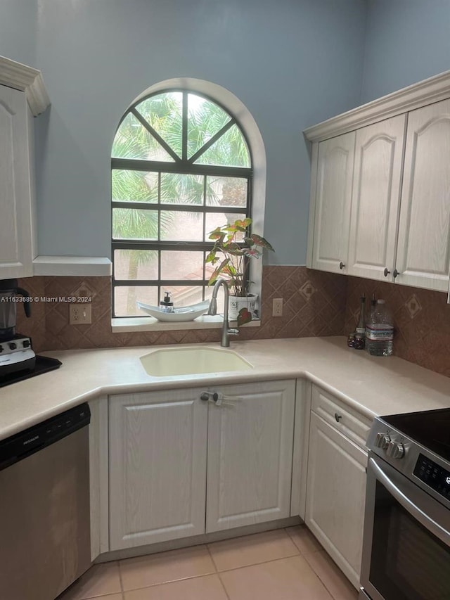 kitchen with stainless steel appliances, light tile patterned floors, sink, and white cabinets