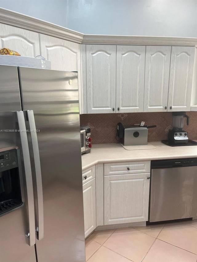 kitchen with white cabinetry, decorative backsplash, light tile patterned flooring, and stainless steel appliances