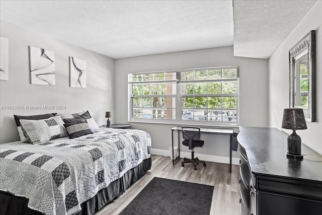 bedroom featuring light wood-type flooring and a textured ceiling