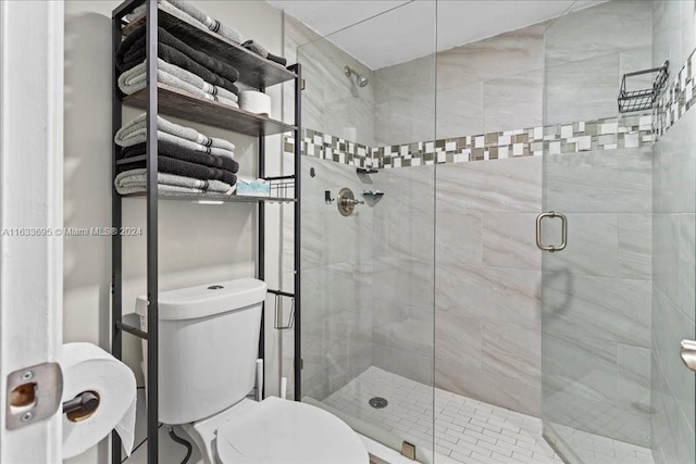 bathroom with a shower with shower door and toilet