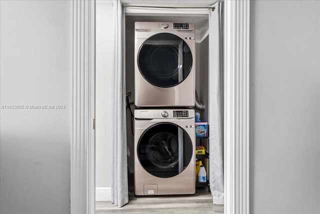 laundry room featuring stacked washer and clothes dryer and light wood-type flooring