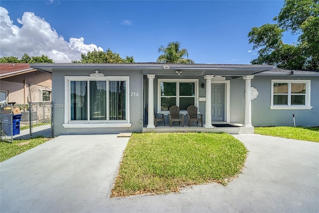 216 SW 6th St, Hallandale Beach, FL 33009 - view of front of property featuring a front yard, stucco siding, covered porch, and fence
