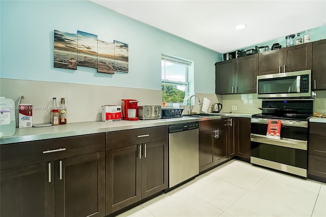 216 SW 6th St, Hallandale Beach, FL 33009 - kitchen featuring light countertops, stainless steel appliances, dark brown cabinetry, a sink, and light tile patterned floors