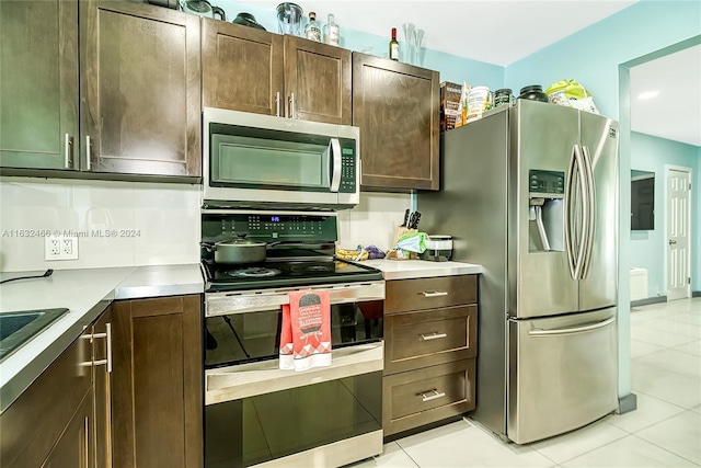 216 SW 6th St, Hallandale Beach, FL 33009 - kitchen with dark brown cabinetry, light countertops, light tile patterned floors, and appliances with stainless steel finishes