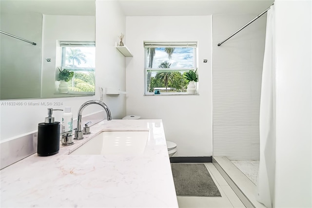 bathroom featuring plenty of natural light, vanity, tile patterned floors, and toilet