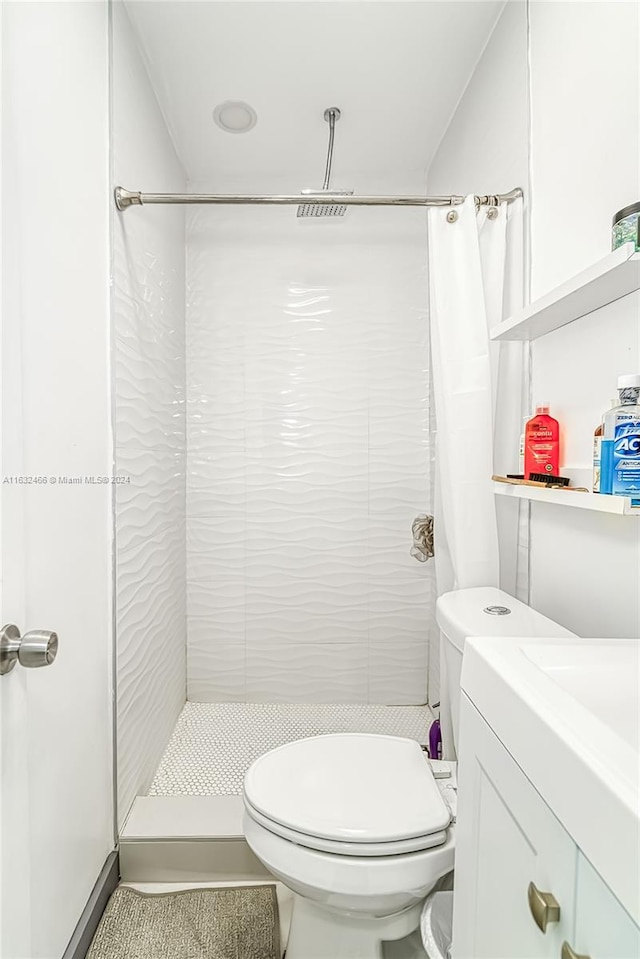 bathroom featuring walk in shower, toilet, and vanity