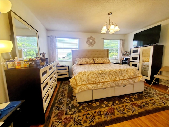 bedroom with multiple windows, a chandelier, and dark wood-type flooring