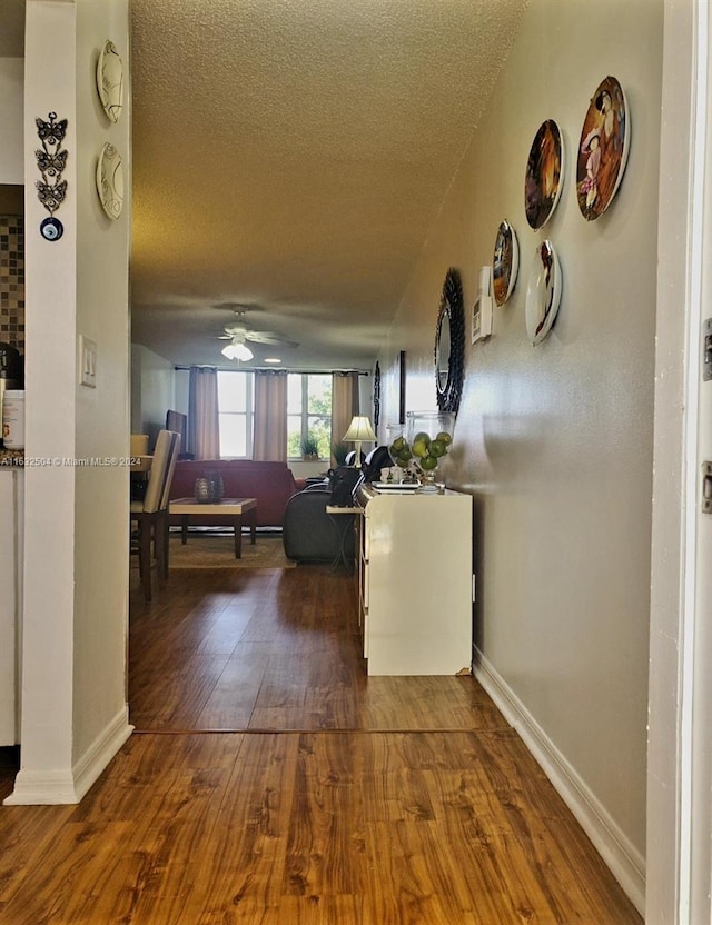 corridor with hardwood / wood-style flooring and a textured ceiling